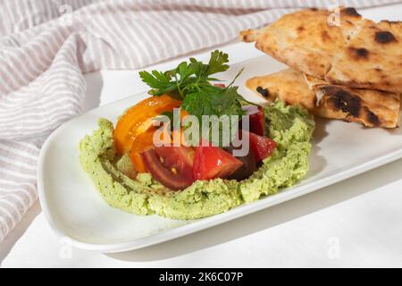 Edamame Hummus mit frischen Tomaten auf weißem Hintergrund für die Speisekarte des Restaurants. Stockfoto