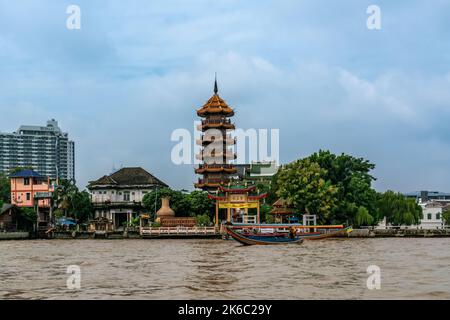 Ein Langschwanz-Boot liegt am Pier des Che Chin Khor-Tempels und der Pagode in Bangkok, Thailand. Horizontale Aufnahme. Stockfoto