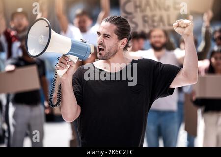 Ein junger Mann, der während eines Protestes durch ein Megaphon schreit. Stockfoto