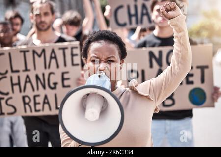 Die Welt kann nicht selbstgefällig bleiben: Eine junge Frau, die vor einem Protest durch ein Megaphon schreit. Stockfoto