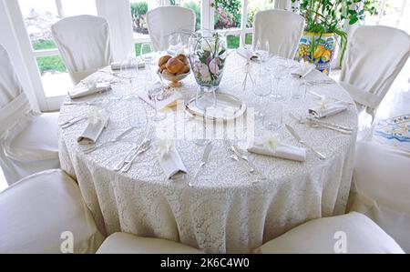 Brautmise en Place mit weißer Tischdecke aus Spitze und silbernem Besteck. Stockfoto