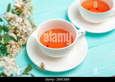 Grüner Tee in einer keramischen Tasse mit Ästen blühender Äste Stockfoto