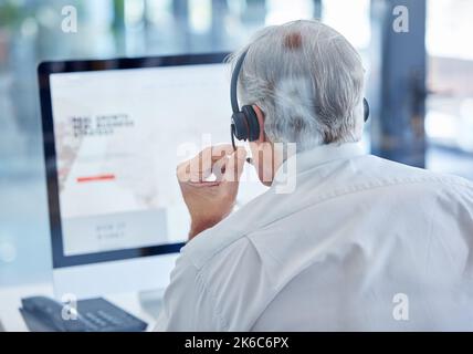 Kunden zu den richtigen Verkaufsstellen leiten. Rückansicht eines reifen Call Center-Agenten, der an einem Computer in einem Büro arbeitet. Stockfoto