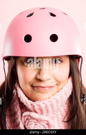 Warm und sicher. Eine reife Frau, die allein im Studio steht und einen Helm trägt. Stockfoto