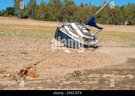 Segelboot gestrandet an Land wegen Dürre mit blauen Himmel Bäume im Hintergrund horizontal Stockfoto