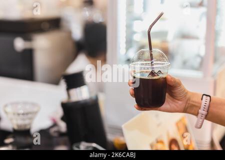 Frau Kundin hält Eiskaffee in Kunststoffglas mit Stroh. Stockfoto