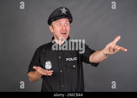 Frustrierter kaukasischer Mann mit Polizeiuniform-Kostüm vor grauem Studiohintergrund Stockfoto