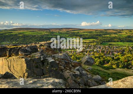 The Cow & Calf Rocks (landschaftlich reizvolle Aussicht auf das Dorf im Wharfe Valley, Hochmoorlandschaft, blauer Himmel) - Ilkley Moor, West Yorkshire, England. Stockfoto