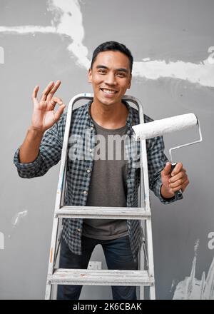Ein attraktiver asiatischer Mann zeigt eine gute Handbewegung, während er sich zum Malen vorbereitete Stockfoto