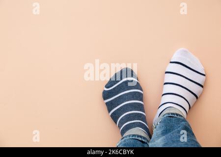 Ungerade Socken Tageskonzept. Beine in verschiedenen Socken auf blauem Hintergrund. Draufsicht. Stockfoto