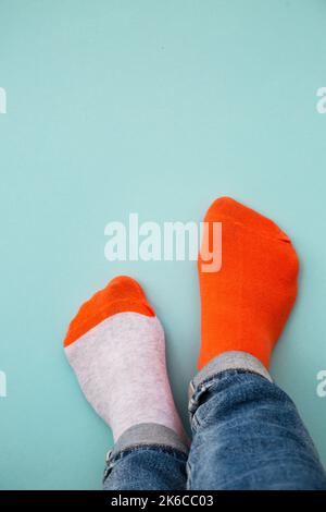 Ungerade Socken Tageskonzept. Beine in verschiedenen Socken auf blauem Hintergrund. Draufsicht. Stockfoto