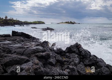 Sehr schöne Wellen, die über die Felsen am Strand der Insel Floreanda, Galapagos, Ecuador, krachen Stockfoto