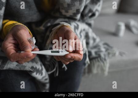 Teilansicht eines erkrankten Mannes, der elektronische Geräte hält, während er an Fieber leidet, Stockbild Stockfoto