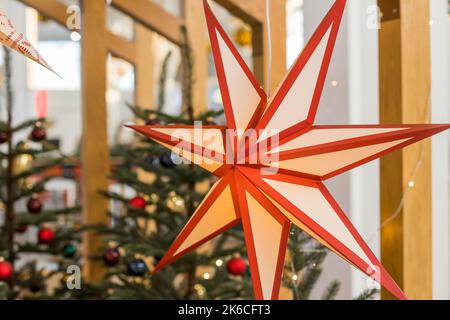 Ein Weihnachtsstern im Fenster. Warmes Licht, Weihnachten, gemütliche Atmosphäre. Adventszeit.Papierblitzlaterne in Sternform. Neujahr Dekoration Stockfoto