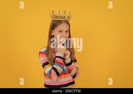 Lächelndes Teenager-Kind in Königskrone auf gelbem Hintergrund Stockfoto