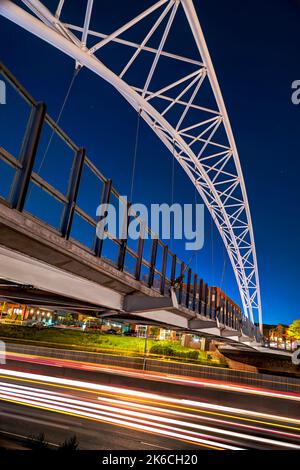 HDR-Bild der Fußgängerbrücke Highland, einer Hängebrücke, die sich über die I-25 in Denver, Colorado erstreckt. Mit leichten Streifen von Autos auf der Autobahn nehmen Stockfoto