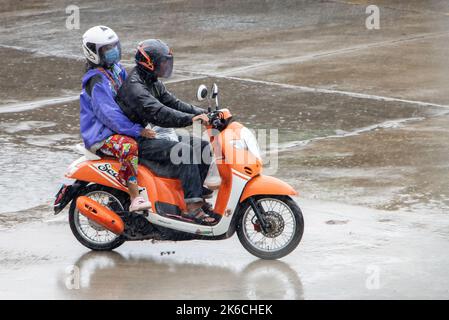 SAMUT PRAKAN, THAILAND, SEP 26 2022, Paar in Regenmänteln fahren bei starkem Regen Stockfoto