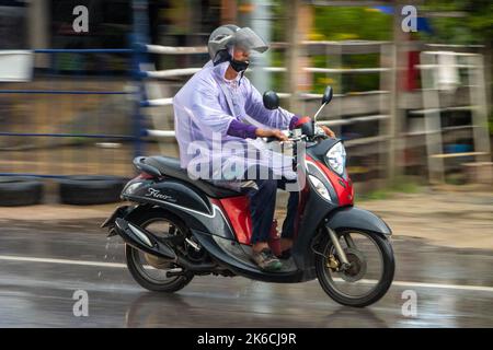 SAMUT PRAKAN, THAILAND, SEP 21 2022, Ein Mann im Regenmantel fährt im Regen mit einem Motorrad auf der Straße Stockfoto