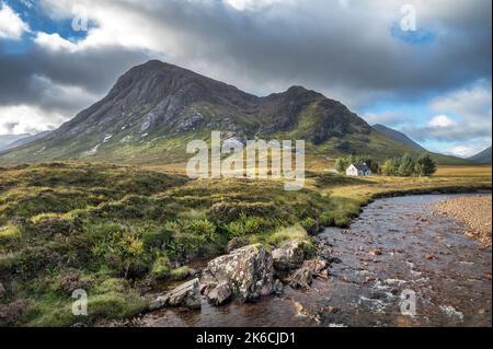 Sanfter Bach neben einer schönen kleinen weißen Hütte im schottischen Hochland Stockfoto