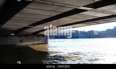 Eine Weitwinkelaufnahme der Unterseite der London Bridge, die eine Säule zeigt, in die der Name im Abendlicht eingemeißelt wurde. Stockfoto