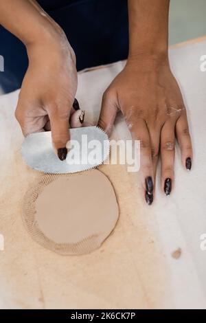 Draufsicht auf afroamerikanische Frau mit Maniküre hält Stahl Schaber beim Formen Ton Stück, Stock Bild Stockfoto