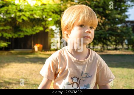 Ein Kind klettert an einem heißen Sommertag in einem Park auf einem Spielplatz auf ein alpines Netz. Kinderspielplatz in einem öffentlichen Park, Unterhaltung und Erholung f Stockfoto