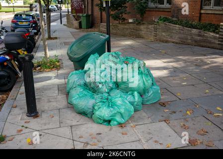 Die grünen Abfallsäcke des Lambeth Council stapelten sich auf der Straße und wurden in London, Großbritannien, zur Abholung bereitgelegt. Stockfoto