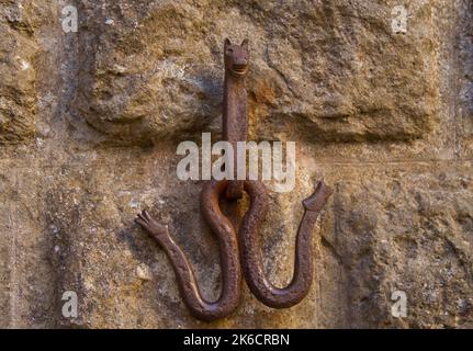 Verrostete Pferdehaken an einer alten Steinwand, die in Form eines Pferdes geformt ist Stockfoto