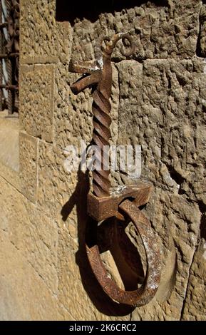 Verrostete Pferde, die einen Ring an einer alten Steinwand in Form eines Pferdes anhängen Stockfoto