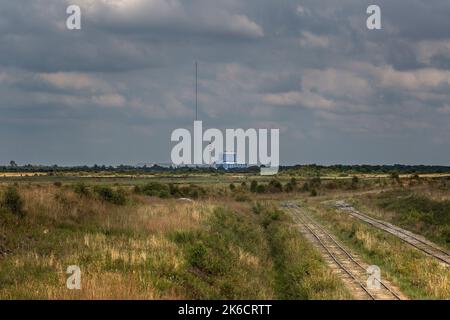 Eine alte Eisenbahnkreuzung für den Torftransport durch Bord na Móna. In der Ferne das Torfkraftwerk von Edenderry. Stockfoto