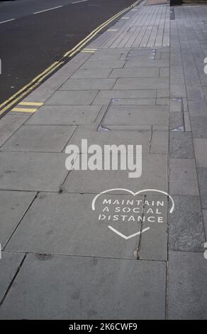 Halten Sie ein soziales Fernpflaster Herz Zeichen auf den Straßen von London Palace Street UK. Stockfoto