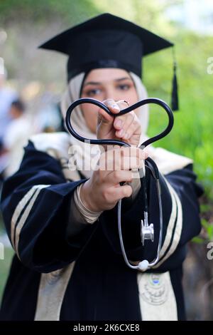 Gaza-Stadt, Gazastreifen, Palästina. 12. Oktober 2022. Gaza, Palästina. 12. Oktober 2022. Die Islamische Universität von Gaza hält in Gaza City eine Abschlussfeier für die weiblichen Studenten ab, die einen Bachelor-Abschluss in Allgemeinkrankenpflege am Institut absolvieren. Familienmitglieder der neu graduierten Krankenschwestern nahmen an der Zeremonie Teil (Bildquelle: © Ahmad Hasaballah/IMAGESLIVE via ZUMA Press Wire) Stockfoto