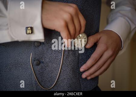 Die Hände eines Mannes in einem eleganten Anzug mit einer Vintage-Armbanduhr Stockfoto