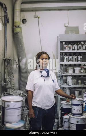 Porträt einer selbstbewussten Malerin, die in der Werkstatt für eine Maldose steht Stockfoto