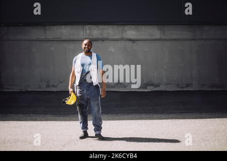 Die ganze Länge der männlichen Bauarbeiter mit Hardhut auf der Straße während des sonnigen Tages stehen Stockfoto