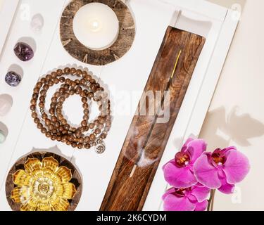 Rosenkranz, Kerzen, Duftstäbchen, Chakra-Steine und Orchideenblumen Stockfoto