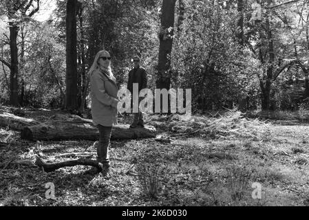 Paar, Frau und Mann, stehen in Wald oder Wald in gestaffelten Positionen und blicken mit Haltung auf die Kamera. Schwarz und Weiß. Stockfoto