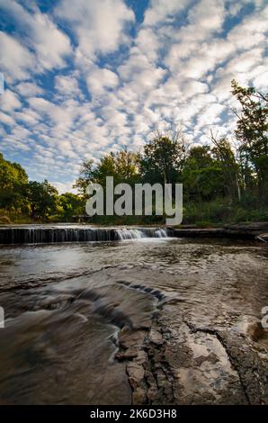 Popcornwolken dominieren den Himmel über den kleinen Felsvorsprüngen auf Praimee Creek im DesPlaines River Fish & Wildlife Area in will County, Illinois Stockfoto