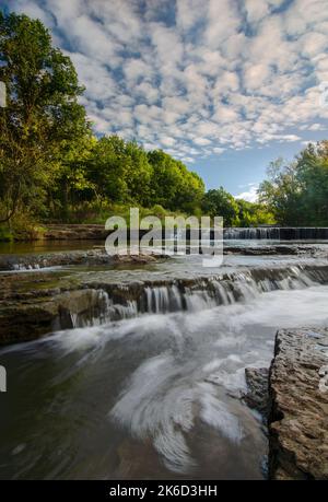 Popcornwolken dominieren den Himmel über den kleinen Felsvorsprüngen auf Praimee Creek im DesPlaines River Fish & Wildlife Area in will County, Illinois Stockfoto