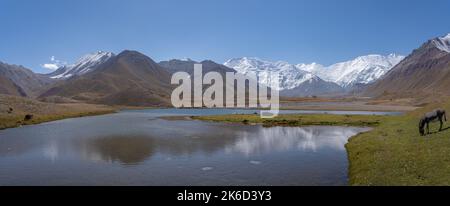 Höhenlandschaftspanorama des schneebedeckten Lenin Peak in der Nähe des Achik Tash Basiscamps mit See und Reflexion, Trans Alay Bergkette, Kirgisistan Stockfoto