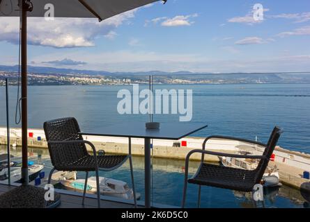 Tisch in einem Café auf einer Panoramaterrasse über dem Yachthafen in Opatija, Kroatien, mit der Stadt Rijeka im Hintergrund Stockfoto