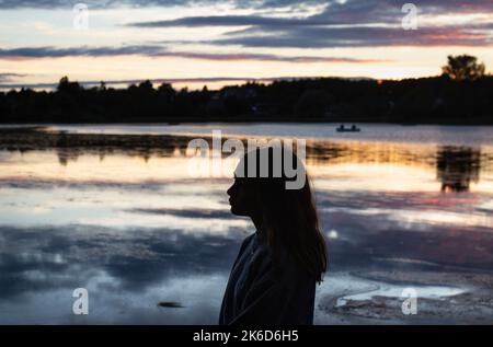 Silhouette eines Mädchens bei Sonnenuntergang am Linlithgow Loch, Schottland Stockfoto