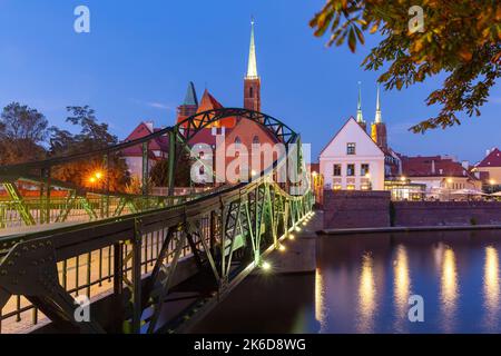 Grüne Eisenbrücke zur Insel Tumsky in der Nachtbeleuchtung am frühen Morgen. Breslau. Polen. Stockfoto