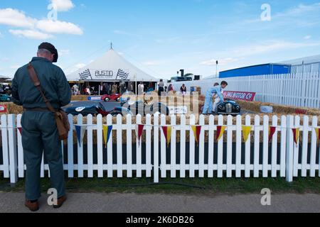 Ein Mann im grünen Overall vor der kleinen Rennstrecke für die Austin J40 Pedalautos, BARC Revival Meeting, Goodwood Motorrennstrecke, Chichester, UK Stockfoto