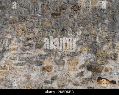 Alte Steinwand Textur mit verschiedenen Natursteinen. Abstrakter Hintergrund von einem Gebäude außen. Verwitterte raue Mauerwerk Muster des Materials. Stockfoto