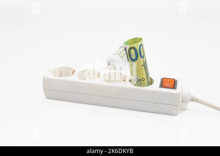 Euro-Banknoten stecken in einer elektrischen Steckerleiste. Konzept der steigenden Strompreise Stockfoto