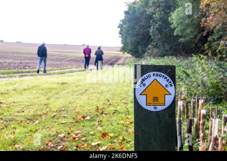 Menschen auf einem Landweg in Essex gehen im Herbst entlang eines öffentlichen Fußweges mit einem Wegweiser des County Council von Essex. Stockfoto