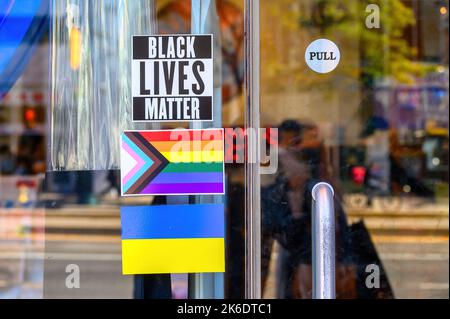 Unternehmen, die drei aktuelle Ursachen befürworten. Aufkleber von Black Lives Matter, der Pride-Flagge und der Flagge der Ukraine Stockfoto