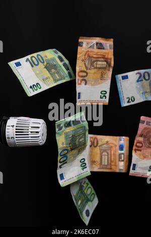 Teure Heizkosten. Thermostat mit mehreren fallenden Euro-Banknoten Stockfoto