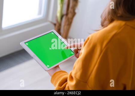 Mädchen mit iPad Tablet Anzeige grünen Bildschirm drücken Browsen Chroma-Taste online eingeben Text lesen Social Media close up Hände 13.12.21 St.Petersburg Stockfoto